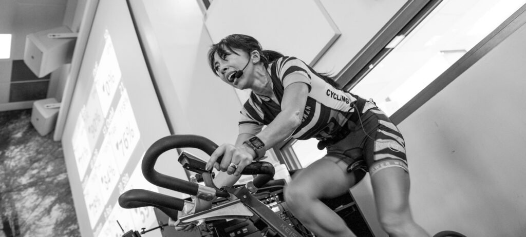 grayscale photography of woman on exercise bike
