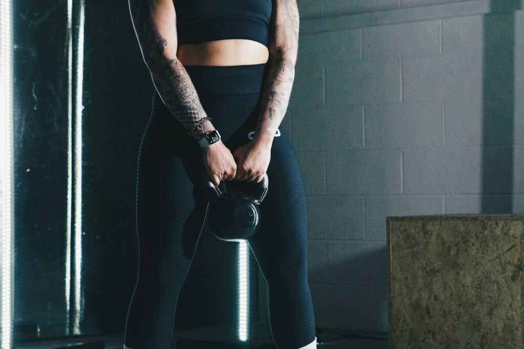 woman in black workout gear holding a black kettlebell