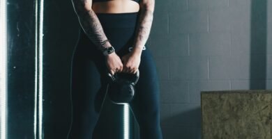 woman in black workout gear holding a black kettlebell