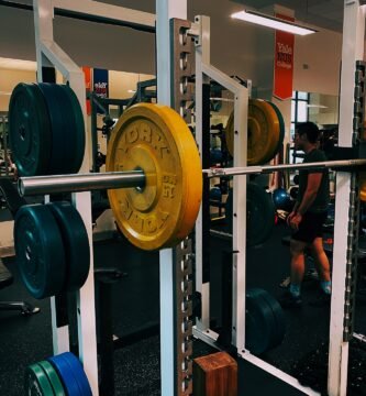 squat rack with barbell and weights on, in a gym
